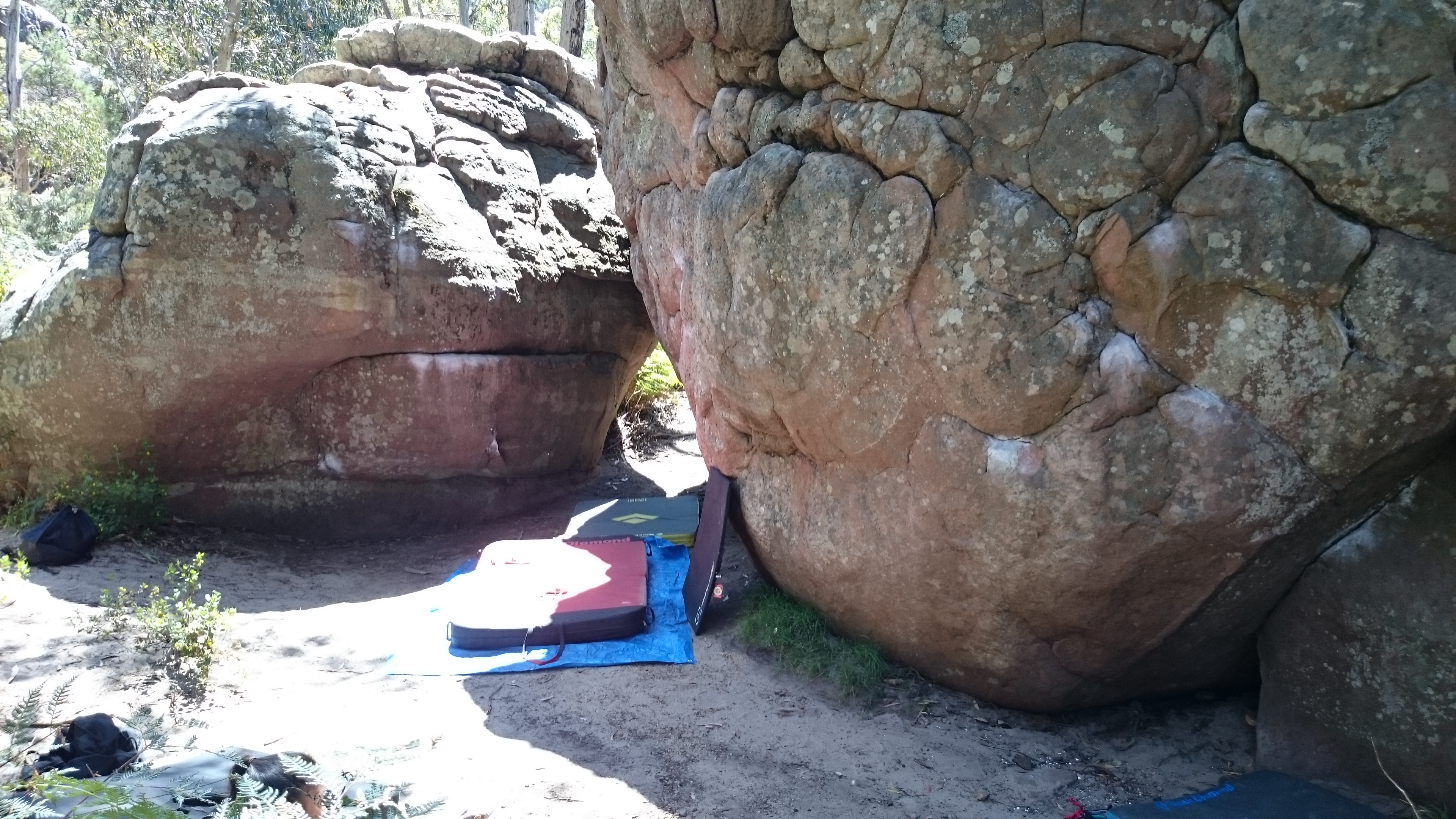 Some chalk-covered boulders with bouldering mats at the base